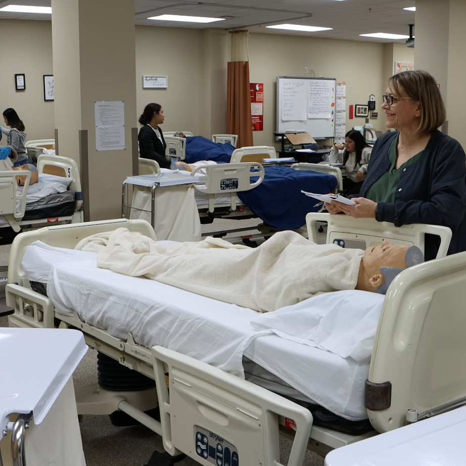  A staff member observes students working with medical dummies